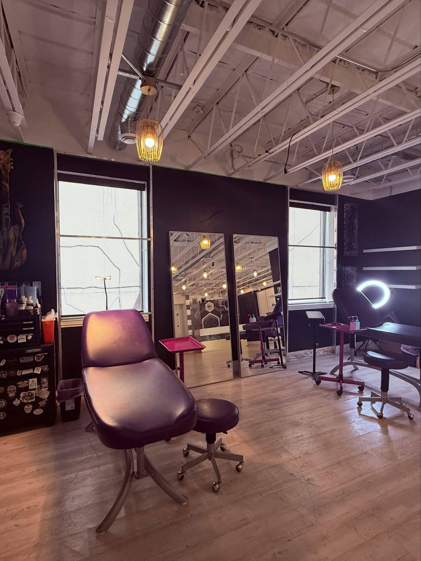 The purple tattoo chair and artist stool under the studio's warm pendant lighting